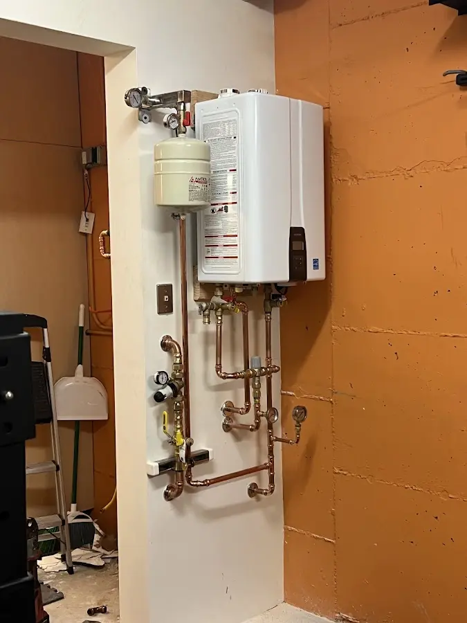 Plumbing technician inspecting water heater connections in Port Washington North